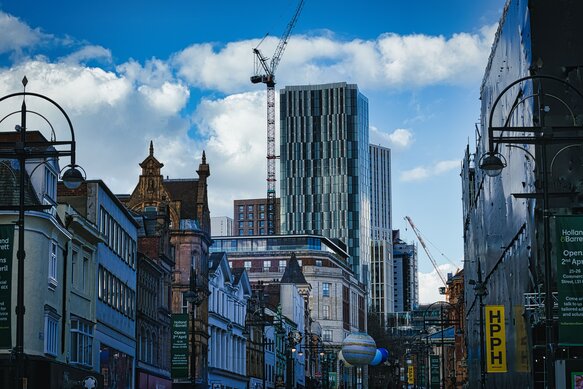Urban cityscape with historic buildings and modern skyscraper under construction against a blue sky with clouds in Leeds UK