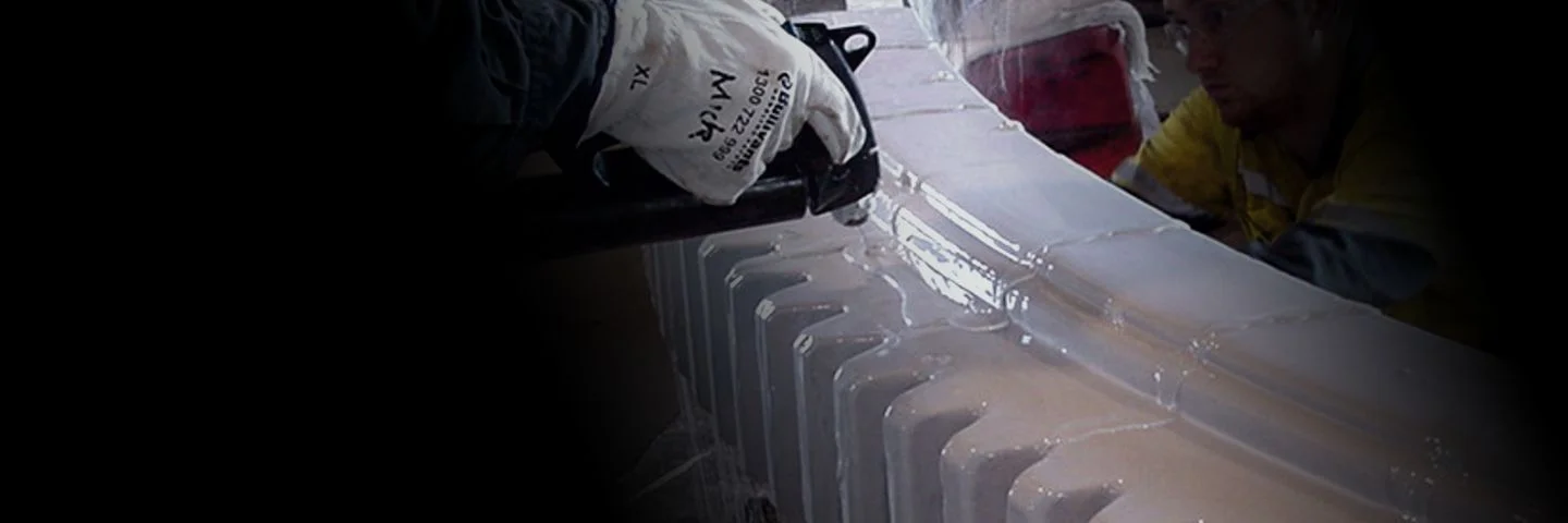 A thermoplastic barrier is sprayed onto a large industrial part.