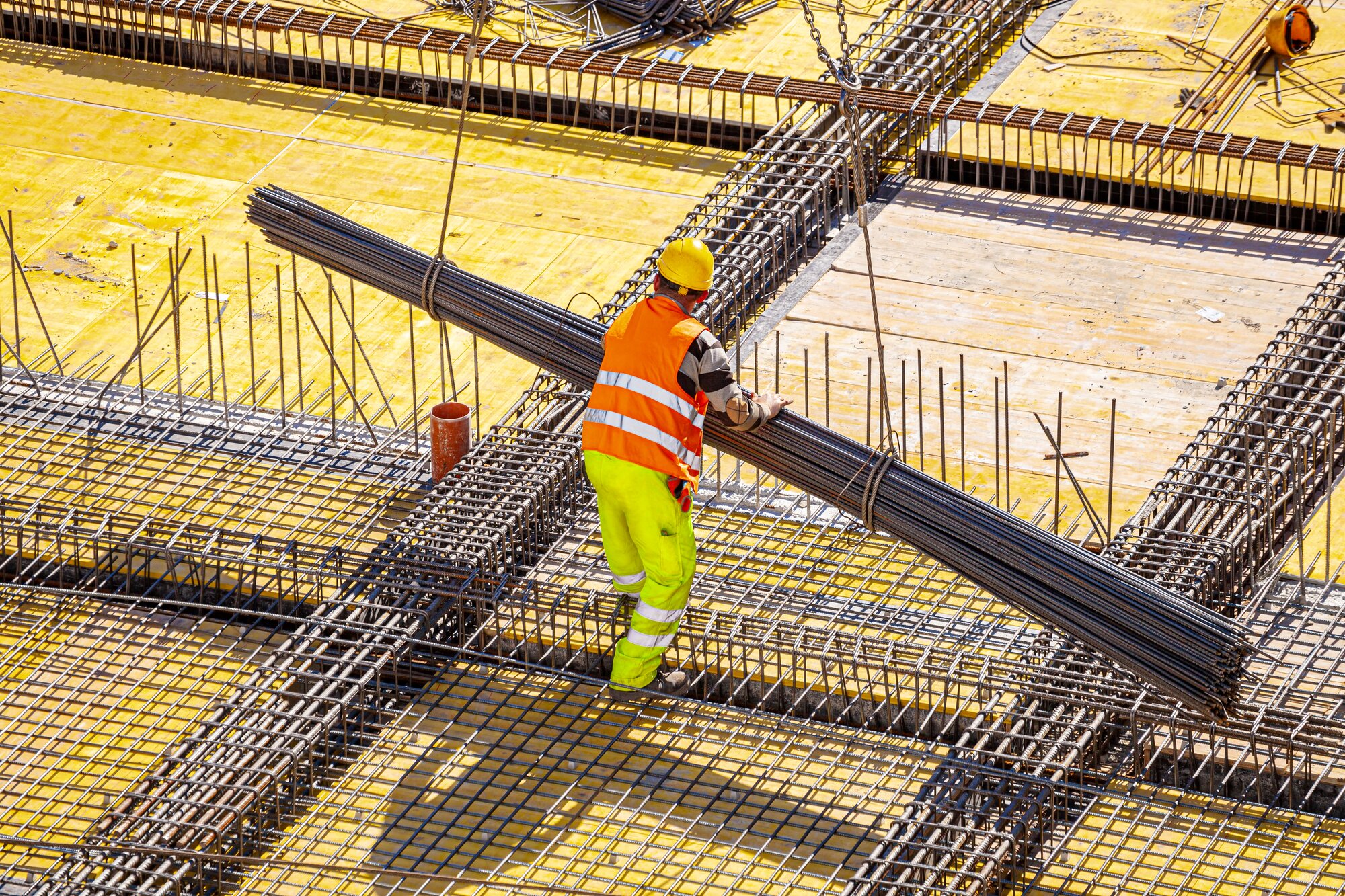 A construction worker lowers a large pile of rebar.