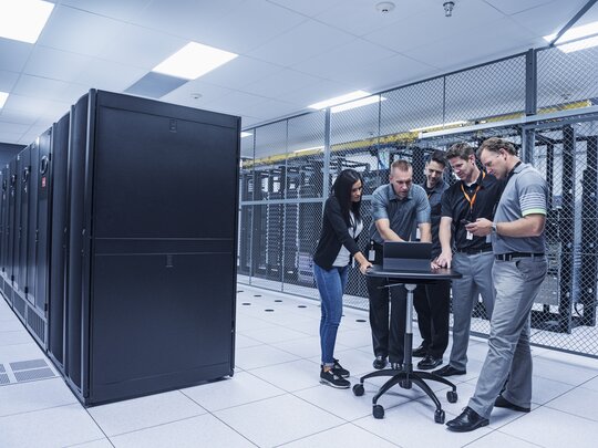 A group of technicians gather in a server room to diagnose problems.