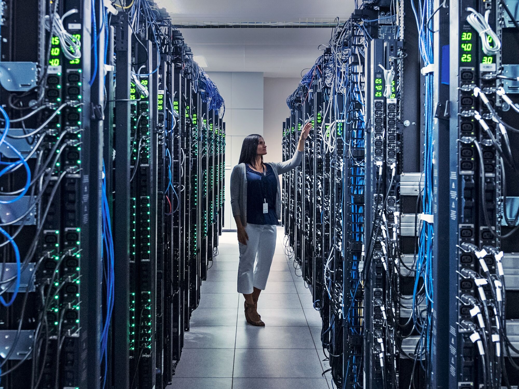 A woman inspecting components inside of a data center.