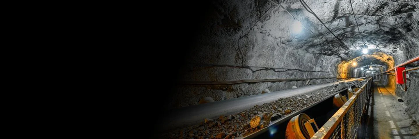 Conveyor belt transferring materials in a brightly lit mineshaft.