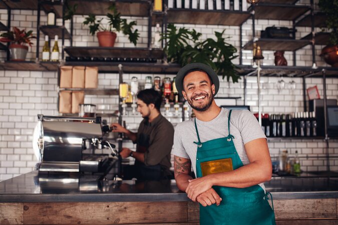 Gastronomie Mitarbeiter lächelt und lehnt sich an die Bartheke