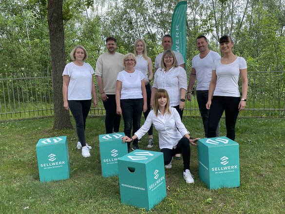 Team Sellwerk Gruppenfoto vom Standort Erfurt mit den Sellwerk Sitzhockern im Vordergrund.