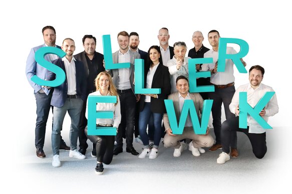 Gruppenfoto von SELLWERK-Mitarbeitenden, die große Buchstaben halten, die das Wort ‚SELLWERK‘ bilden.