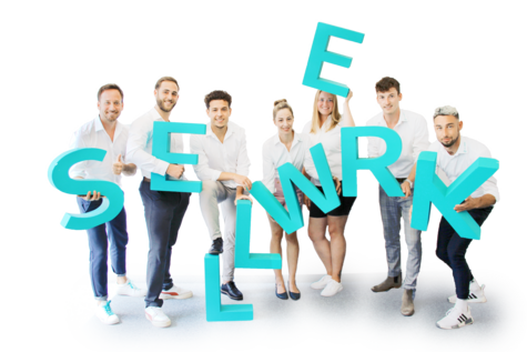 Ein Gruppenbild von SELLWERK Mitarbeitern mit großen SELLWERK Buchstaben in Petrol.