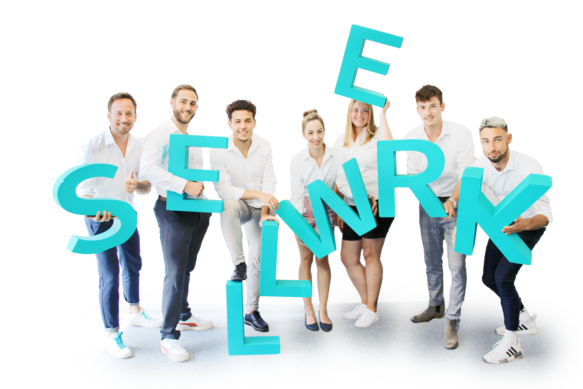 Ein Gruppenbild von SELLWERK Mitarbeitern mit großen SELLWERK Buchstaben in Petrol.