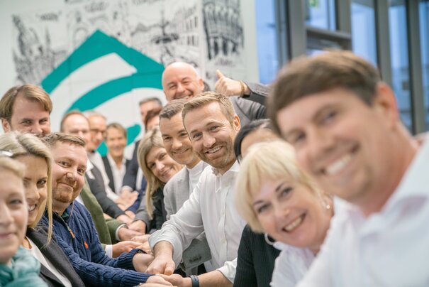 Gruppenfoto mit den Sellwerk Mitarbeitern aus dem Standort Nürnberg die gemeinsam an einem Seil ziehen und in die Kamera lächeln.