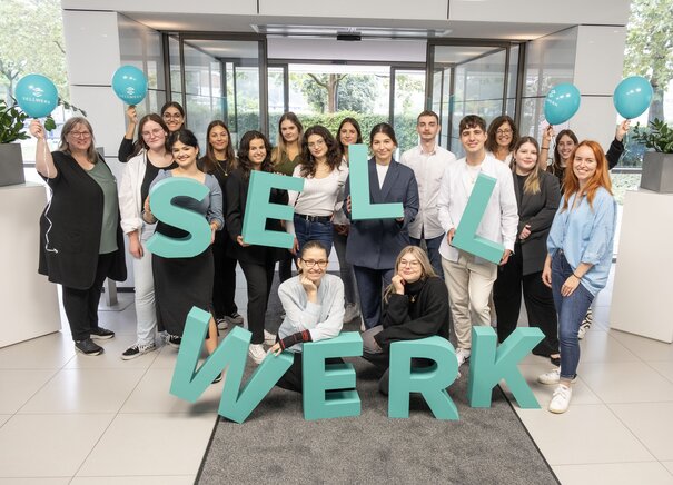 Gruppenfoto von den Azubis und Ausbildern aus dem Team Nürnberg mit dem Sellwerk Logo und Luftballons.