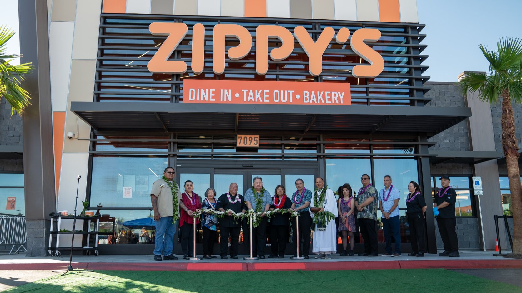 A ribbon cutting ceremony with lei-wearing guests at a new Zippy’s