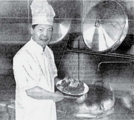 Chef Yufai Cheung holds a plate in the Red Wok kitchen