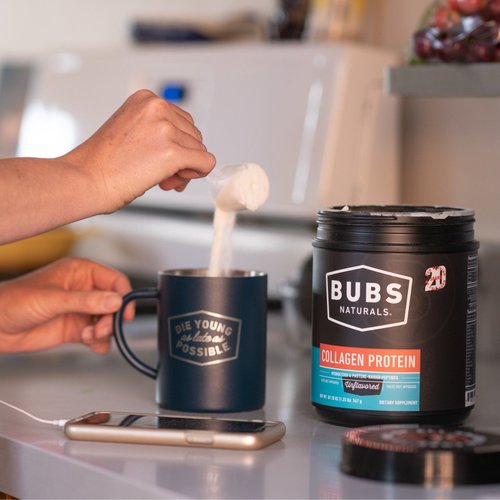 pouring a scoop of BUBS Naturals collagen peptides into a metal, branded mug from a 20oz tub of collagen peptides
