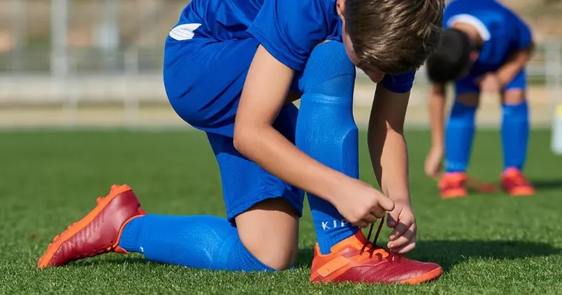 child tying football boot laces