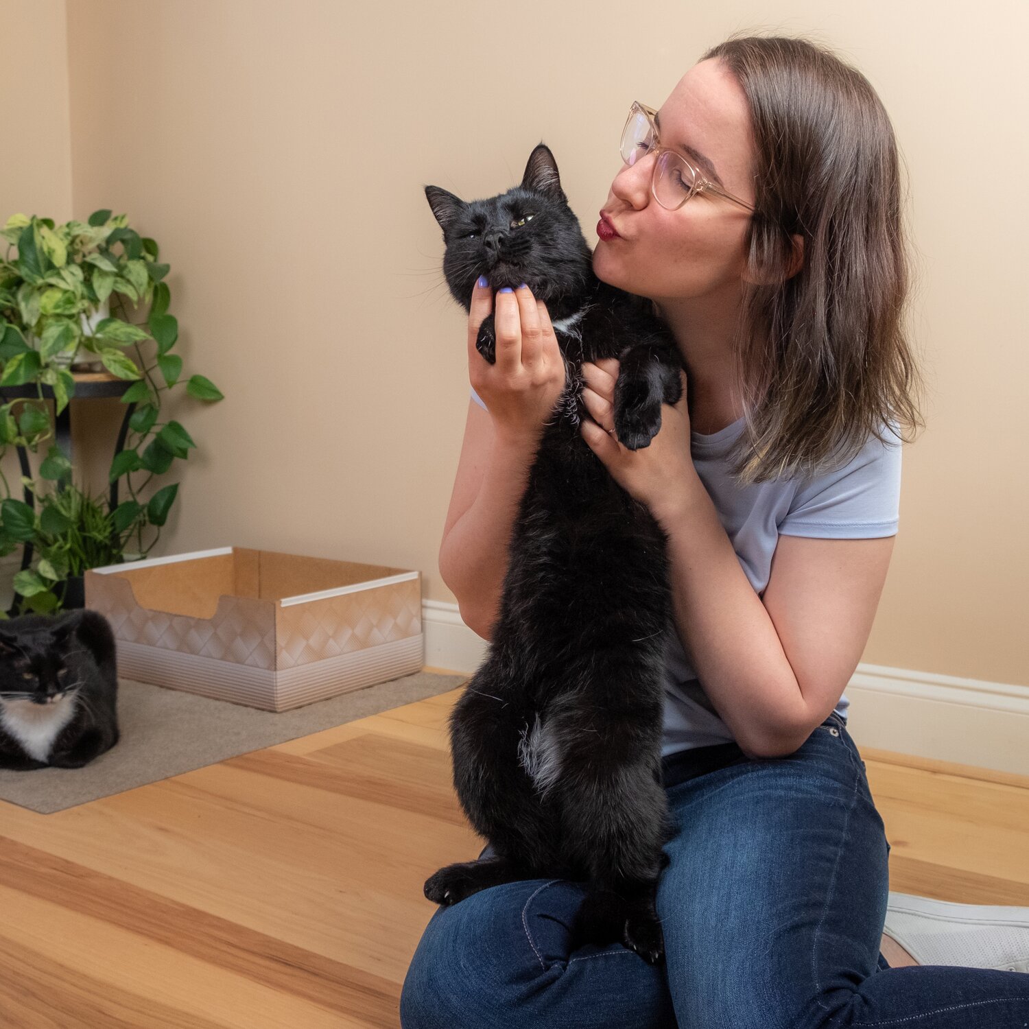 A woman in a clean living room kissing her black cat