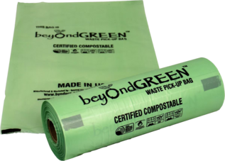 A roll of light green Beyond Green certified compostable waste pick-up bags with one bag unrolled and laid flat behind it.