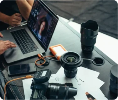Bureau avec un macbook pro, un appareil photo et des objectifs photo.