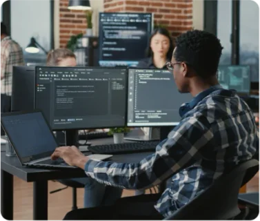 Developpeur sur son ordinateur, il code avec deux écrans
