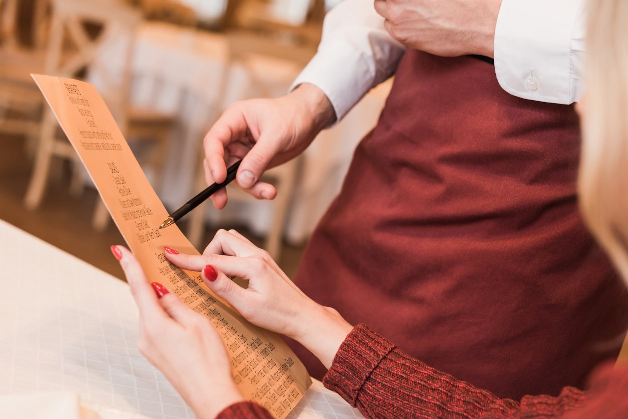 Man pointing to a menu that a woman is holding