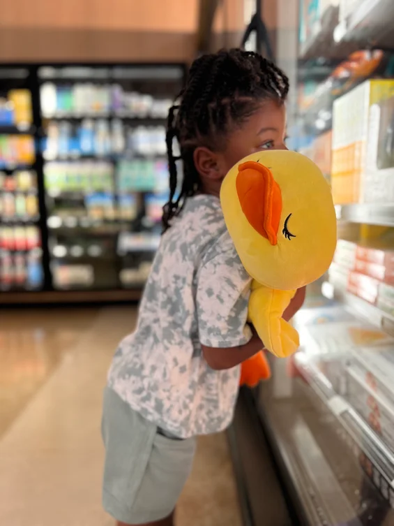A young girl carries our Dolly the Duck plush in a supermarket