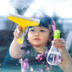 Child using Lovevery spray bottle and squeegee