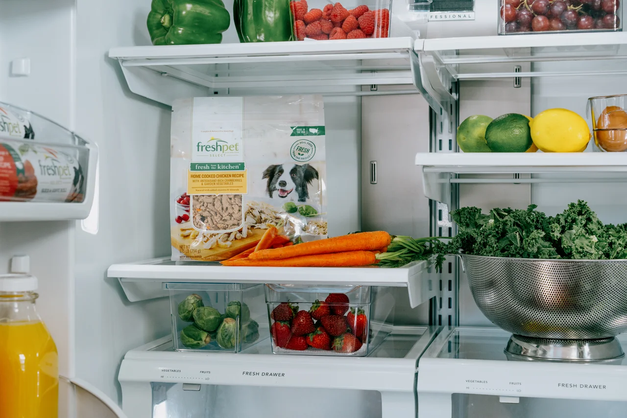 Open refrigerator with Freshpet food packages stored alongside fresh produce.