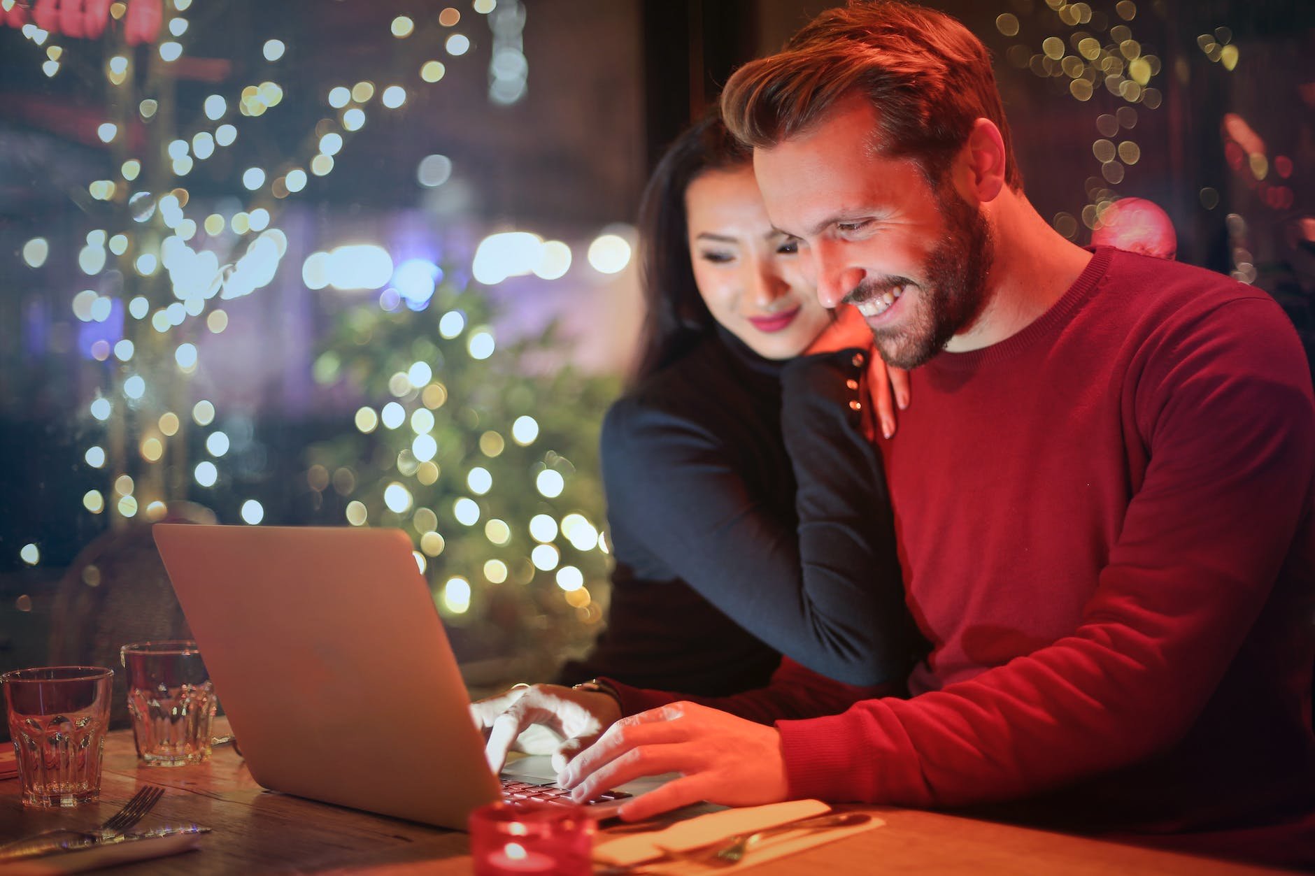 A photo of a couple on the computer together at a dinner table