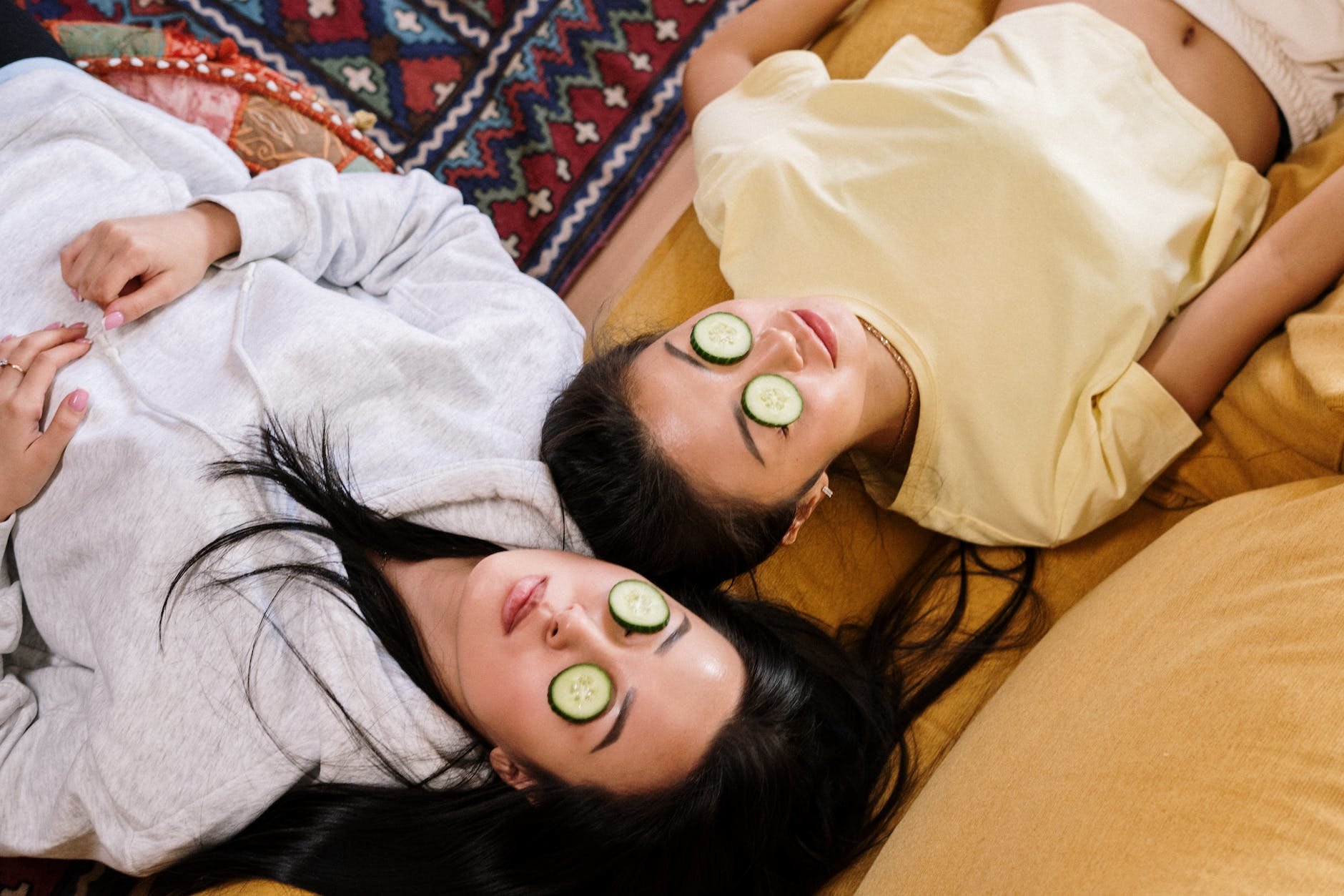 A photo of two people laying down with cucumbers on their eyes