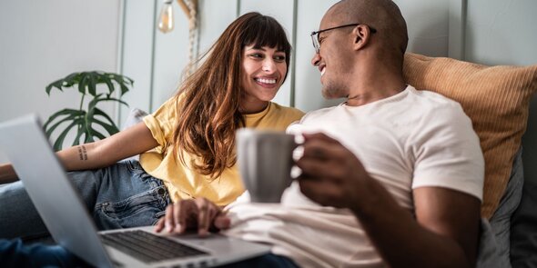 woman and man in bed with laptop and cup of coffee