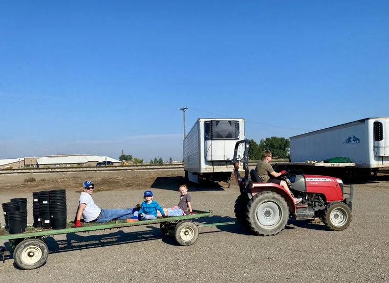 The Tree Source family riding a flatbed wagon behind a tractor at the Rupert, Idaho home farm