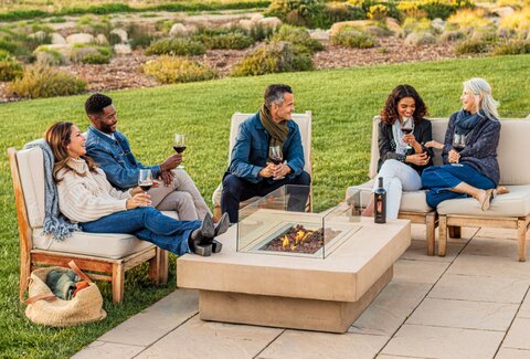 Three women laugh and toast their glasses of red wine in the vibrant and sunny Chef's Garden. 