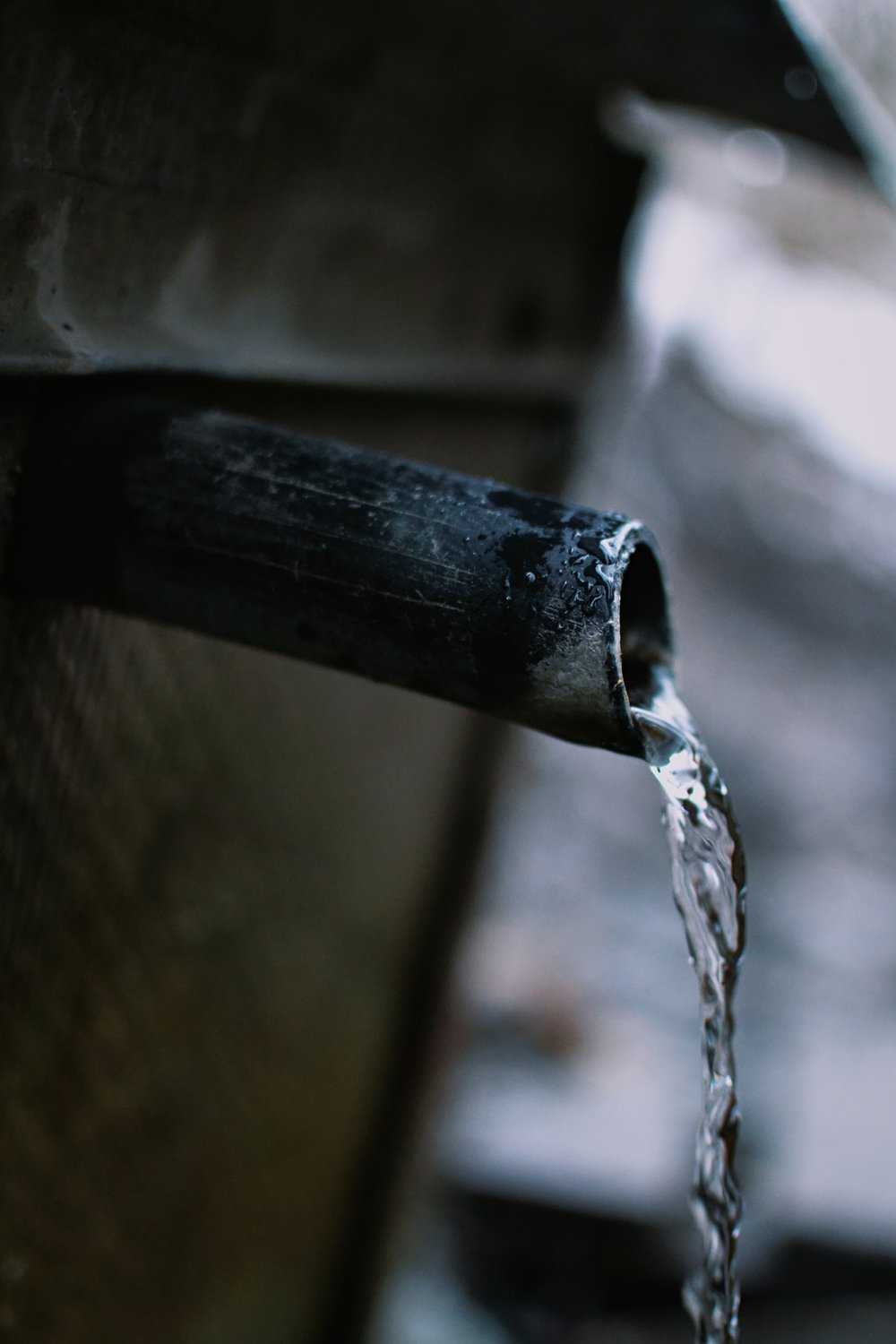 A metal water pipe with a stream of water running out