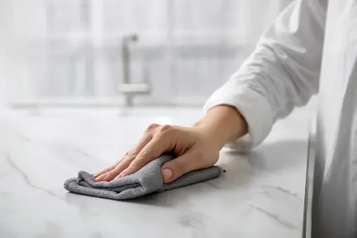 Hand using a cloth to wipe a countertop.