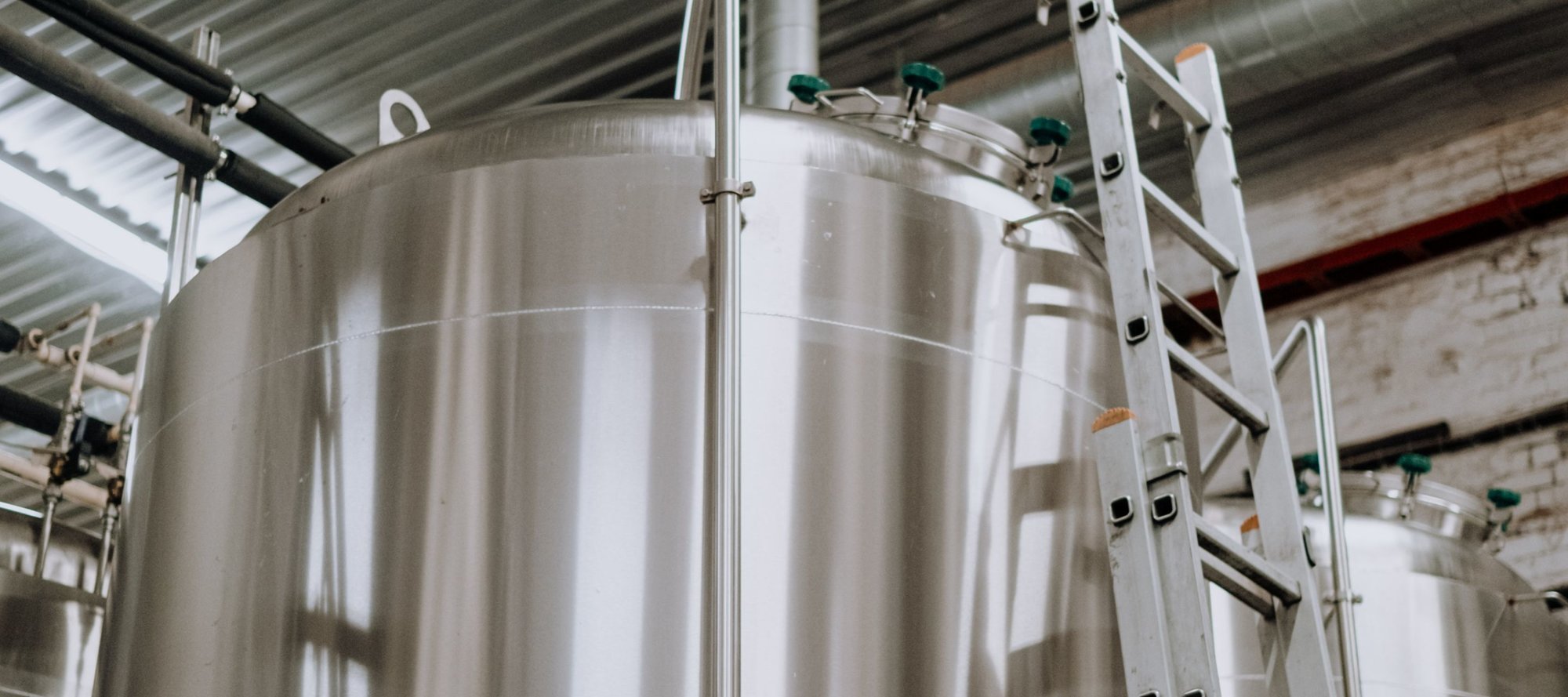 A large silver industrial tank with a ladder leaning against it