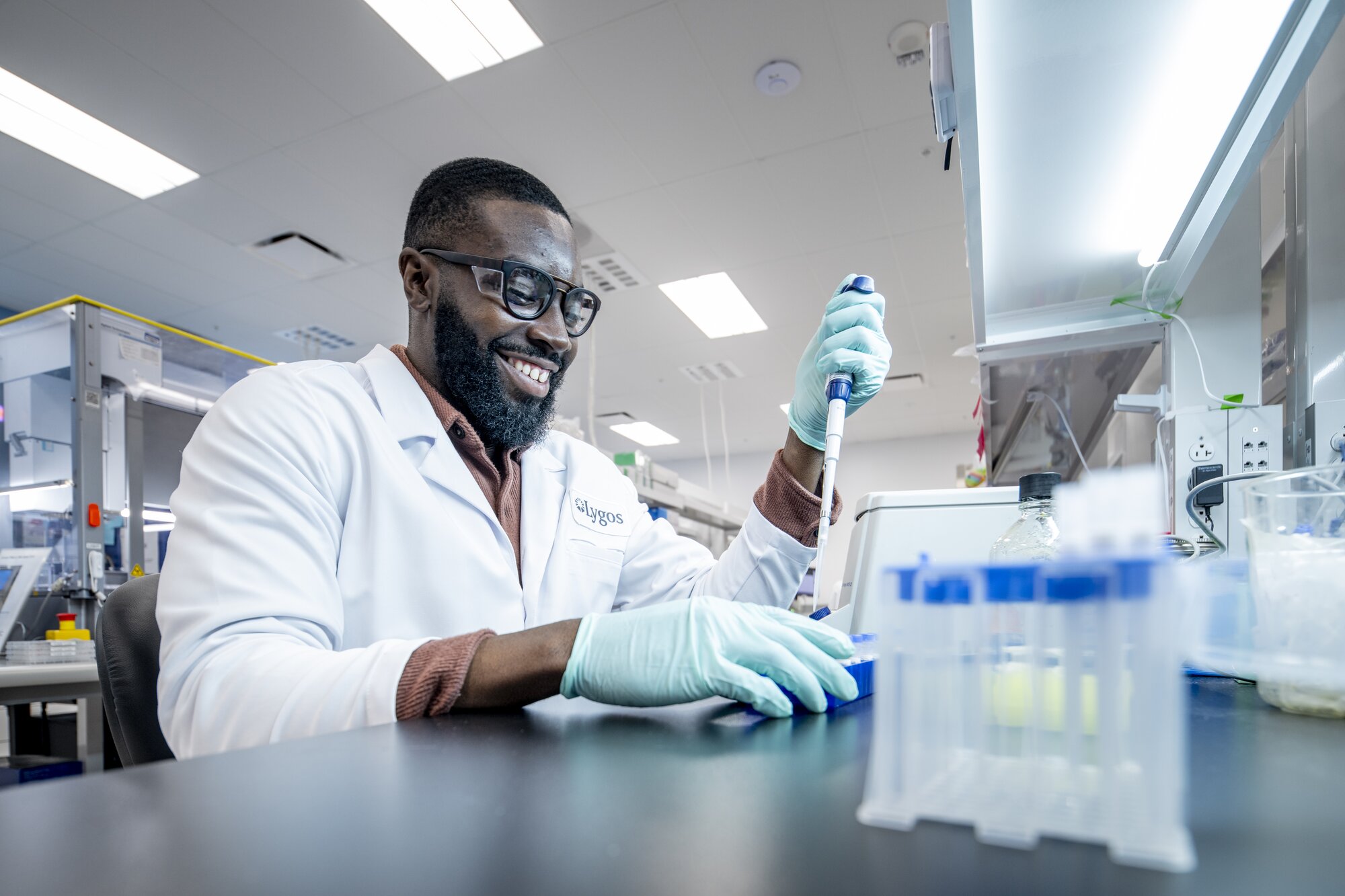 Two people in lab coats wearing eye protection and gloves examining something in their hands