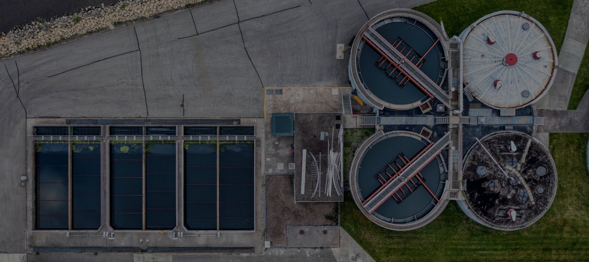 A bird's eye view of a water treatment plant with round water tanks and water being treated in rows