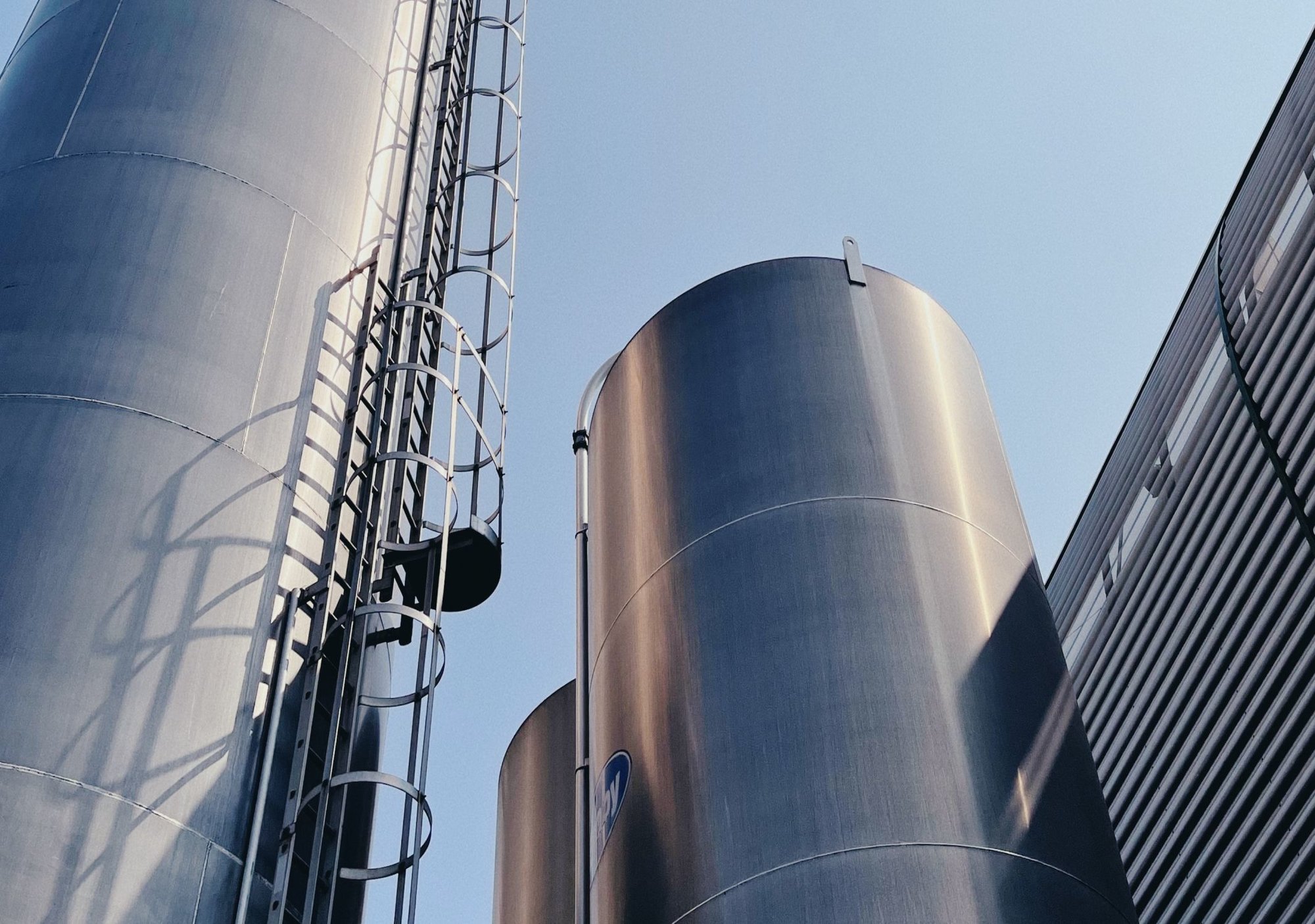 Tall metal silos with ladders set against a blue sky