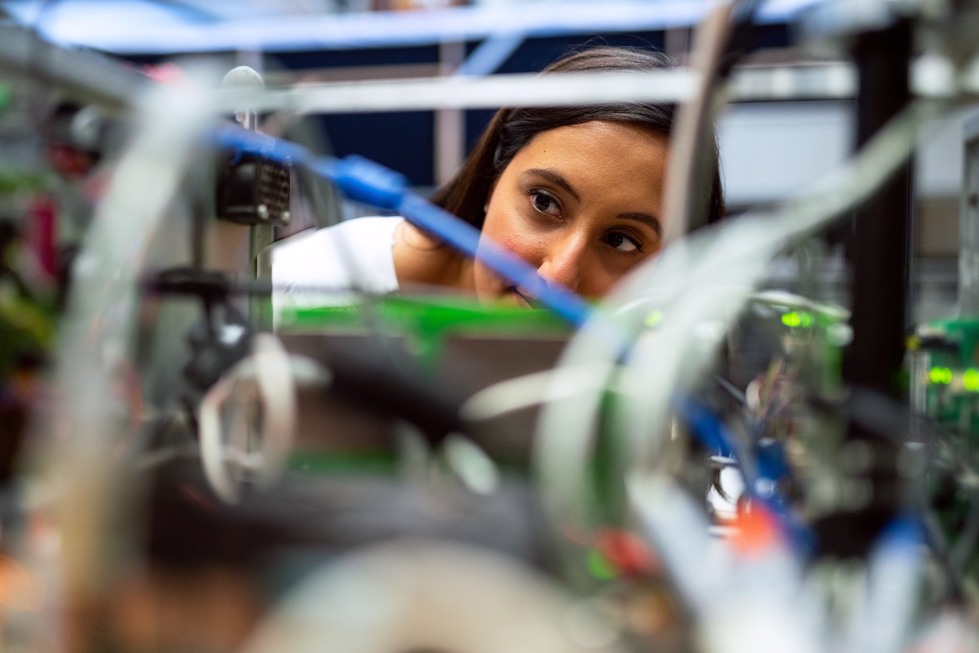 Two people in lab coats wearing eye protection and gloves examining something in their hands