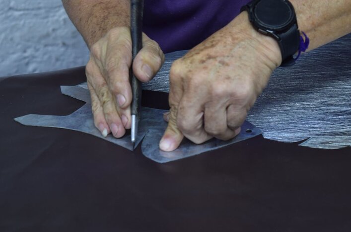 Manos de un artesano marcando y cortando piezas de piel sobre una mesa de trabajo, mostrando la precisión de los oficios mexicanos.