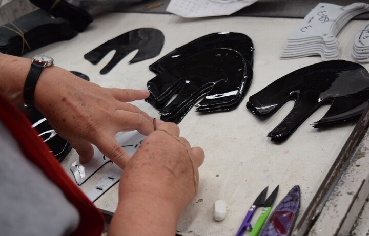Artesano preparando y acomodando piezas negras de material para calzado sobre una mesa, mostrando el trabajo manual de los oficios mexicanos.