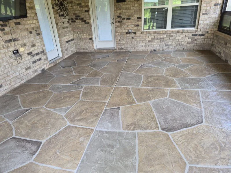 Tan and gray flagstone-pattern concrete patio beneath a covered porch