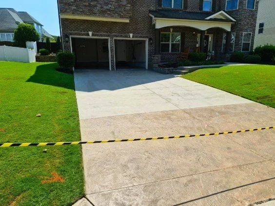 Freshly finished residential concrete driveway leading to a brick home