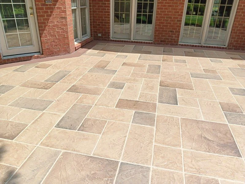 Light ashlar-pattern stamped concrete patio beside a brick home