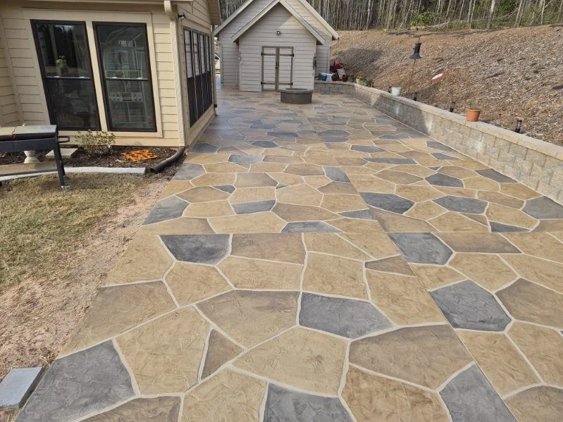 Large multitone flagstone-pattern concrete patio beside a retaining wall