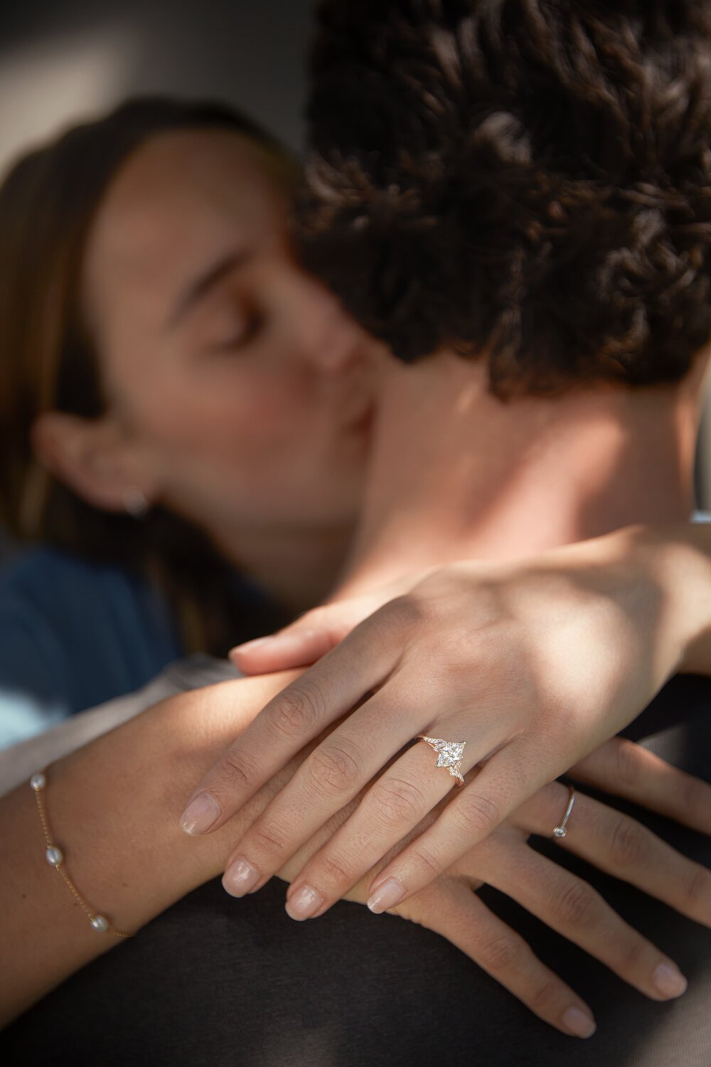 A woman wearing a diamond engagement ring embraces her partner