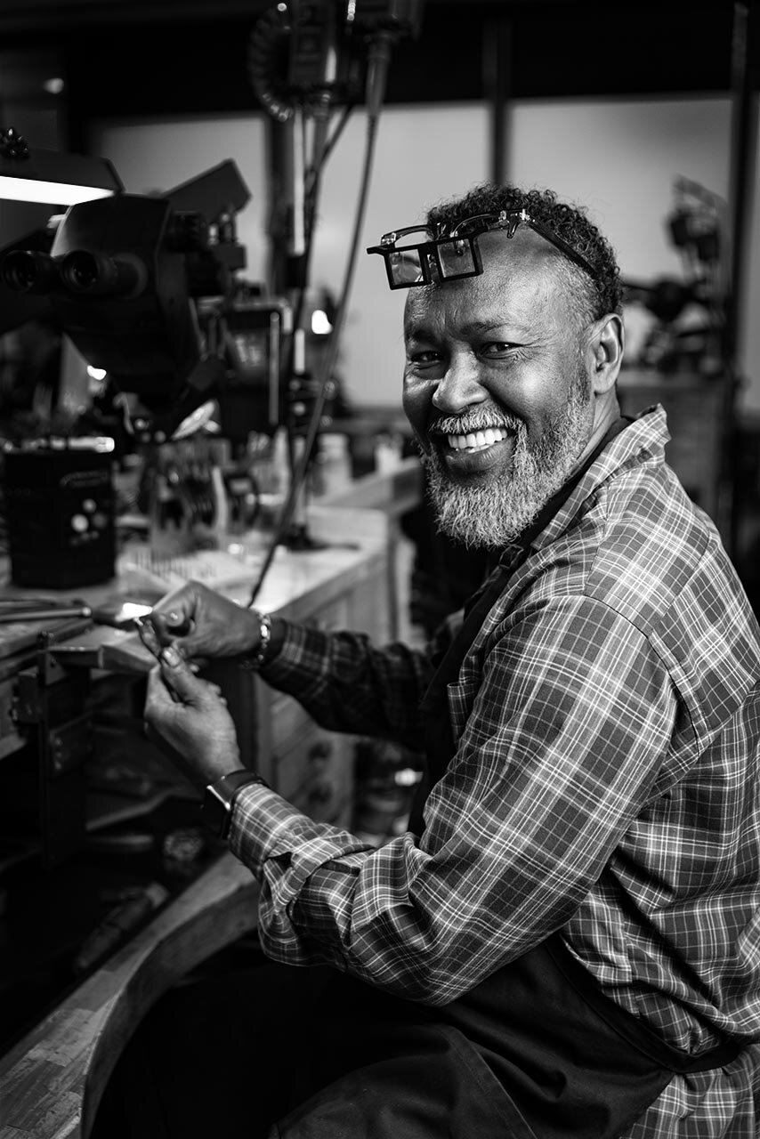 A smiling jeweler at his workbench