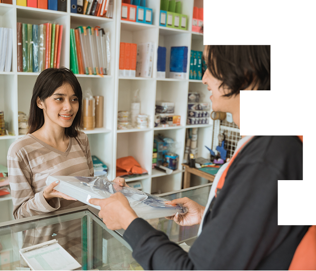 A bookstore employee handing a stack of books to a customer at the counter. Scene of customer service and book purchase in a retail bookstore.