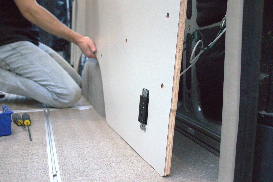 Camper van kit wall panel with built in 110v outlet being removed from the Spritner van.