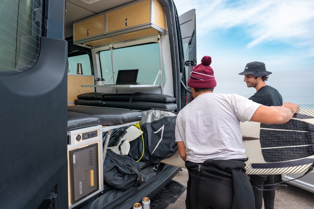 The rear of the van van be converted into storage space. Two men are unloading their surfing gear from the rear storage mode.