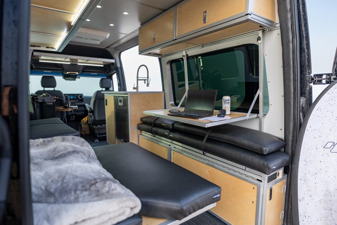 The rear of the Sprinter 144 is converted to a mobile workstation. Utilizing the bed flip-up on one side and the drop-down desk on the other, a comfortable desk is made.