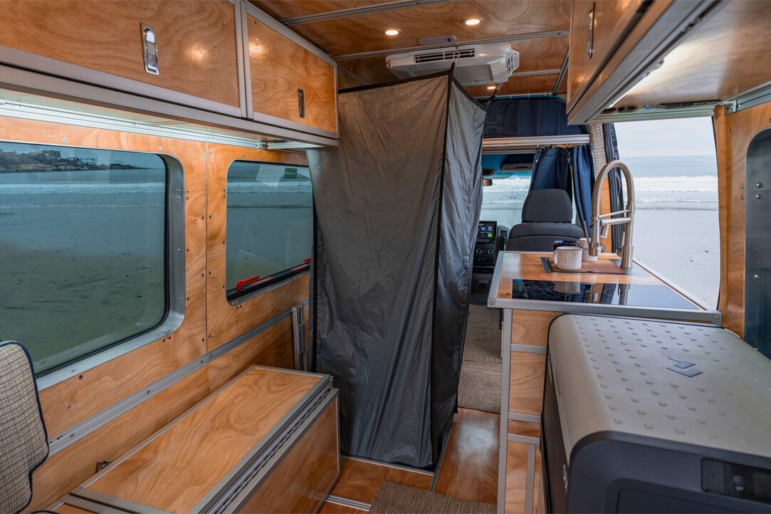 Explore the shower setup inside our camper van 144, showcasing the removable curtain and flush-mount shower pan. Enjoy a refreshing shower experience on your travels.
